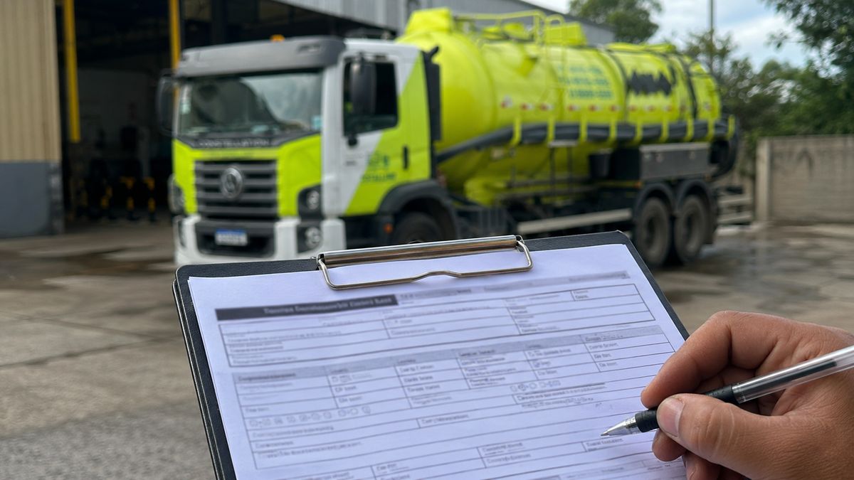 Manifesto de Transporte de Resíduos sendo preenchido em prancheta diante do caminhão da Totallimp